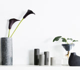Enhance your interior style with a beautiful Calla lily, elegantly arranged in a Zakkia Botanical Vase - Large Black on a shelf.