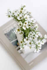 White Alba wax flower faux bush styled in a glass vase on a neutral book for soft, airy shelf decor.