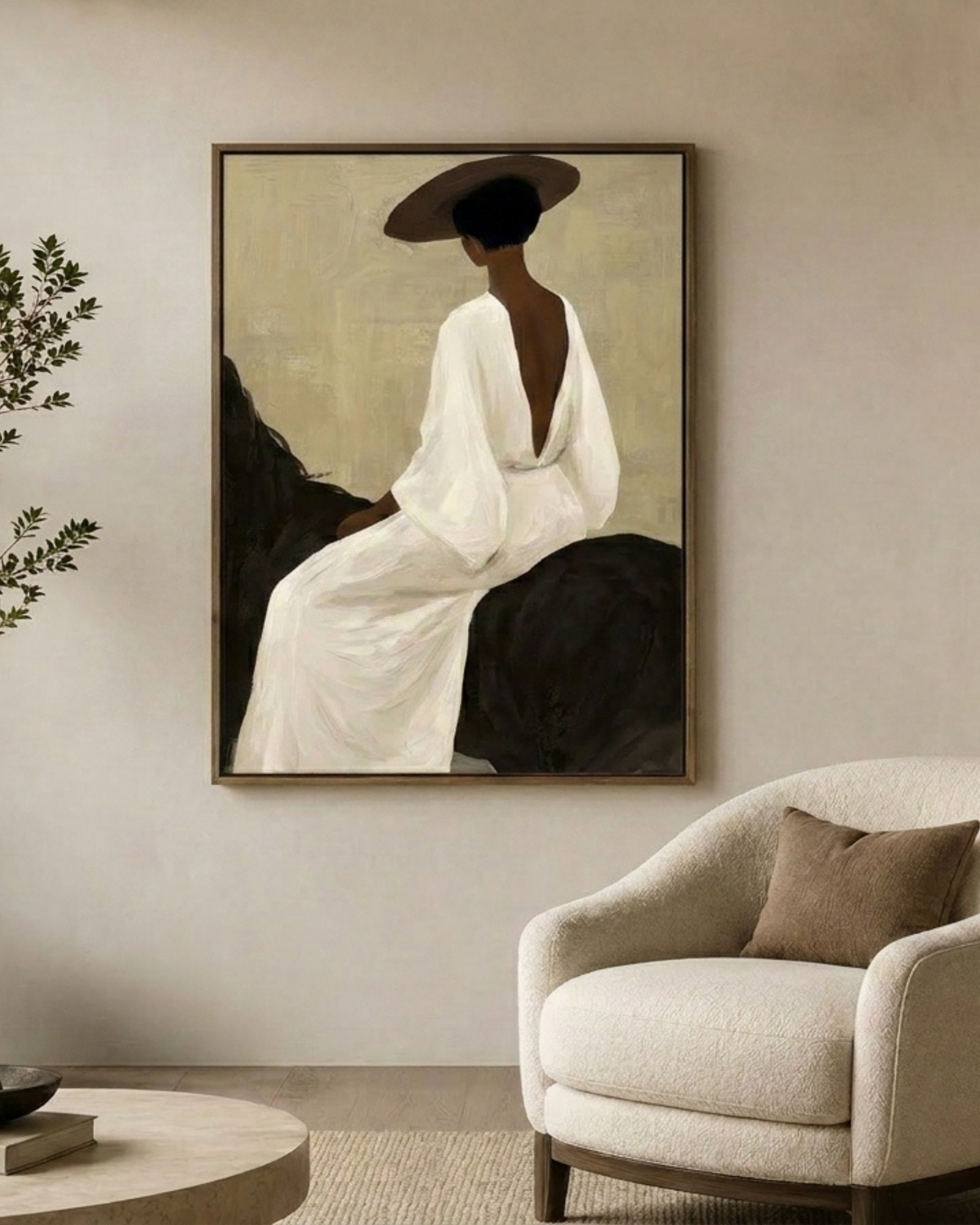 Ali's Sister Print hung above a cream curved armchair beside a round stone coffee table and olive branches