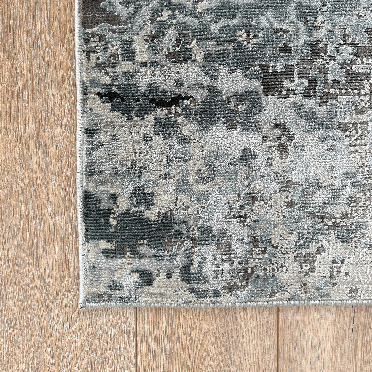 Corner of the grey and ivory abstract rug on a timber floor