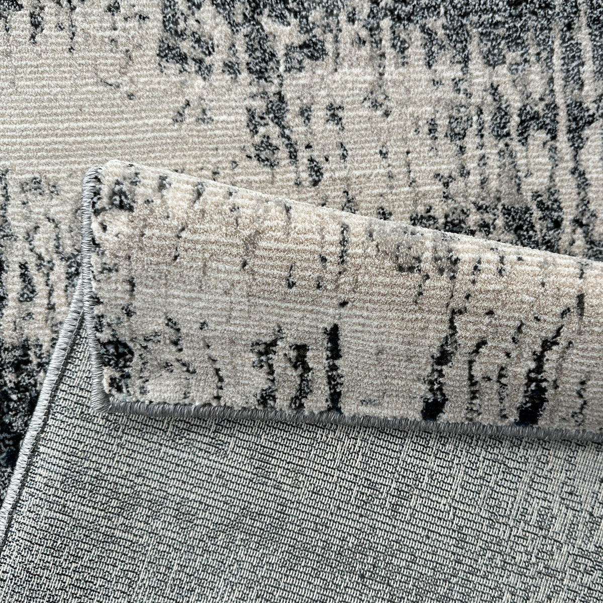 Folded corner of the abstract rug showing the low pile and backing