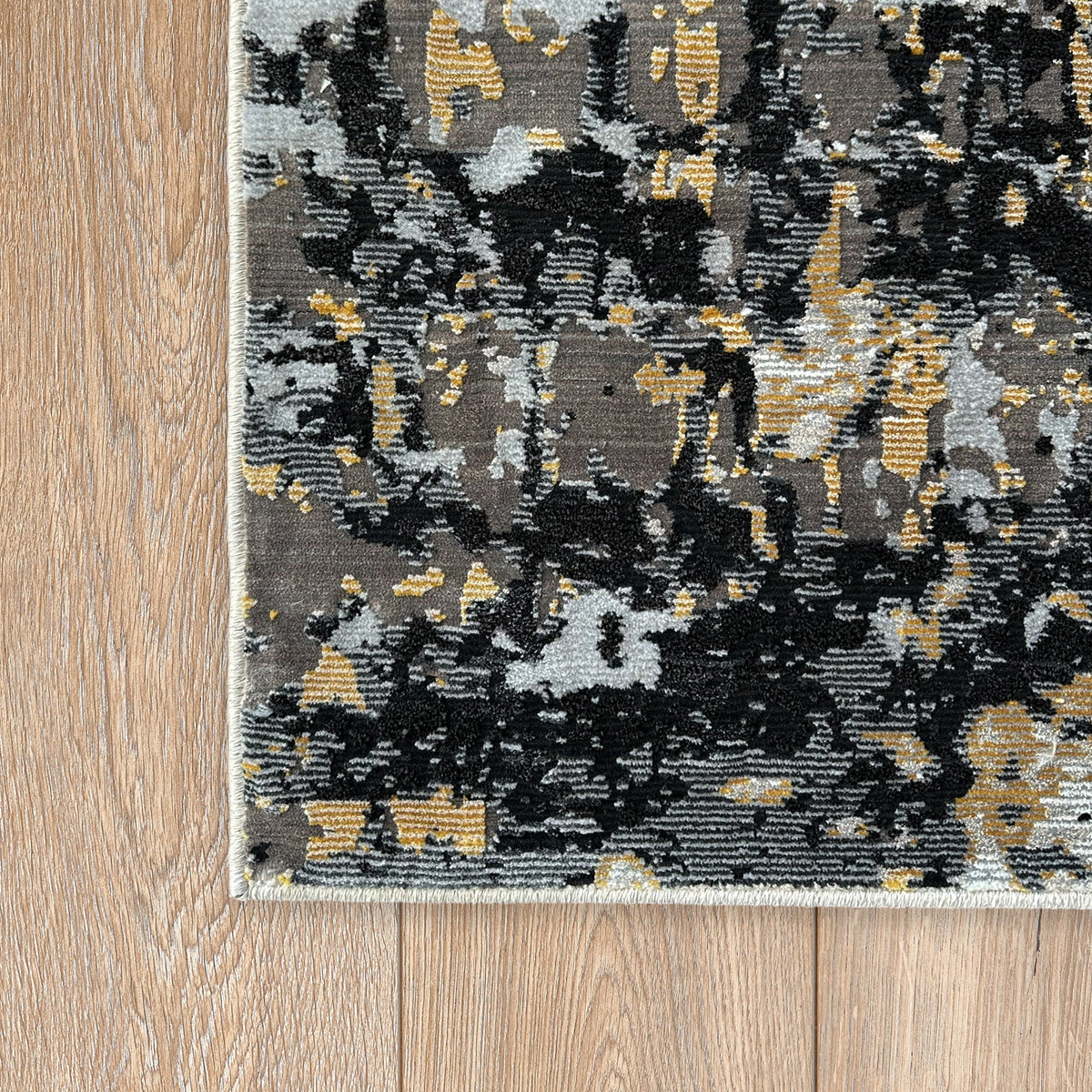 Corner of the black and gold abstract rug on a timber floor
