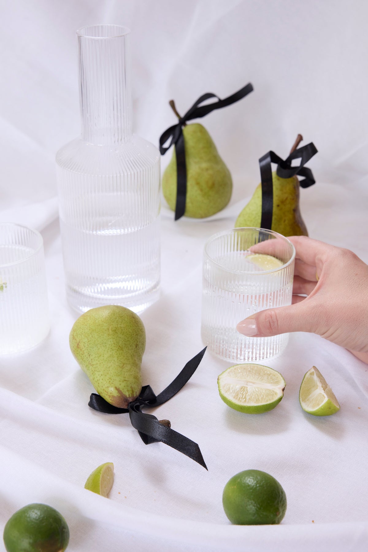 Amalfi fluted water glasses with a fluted decanter, pears and limes on white linen