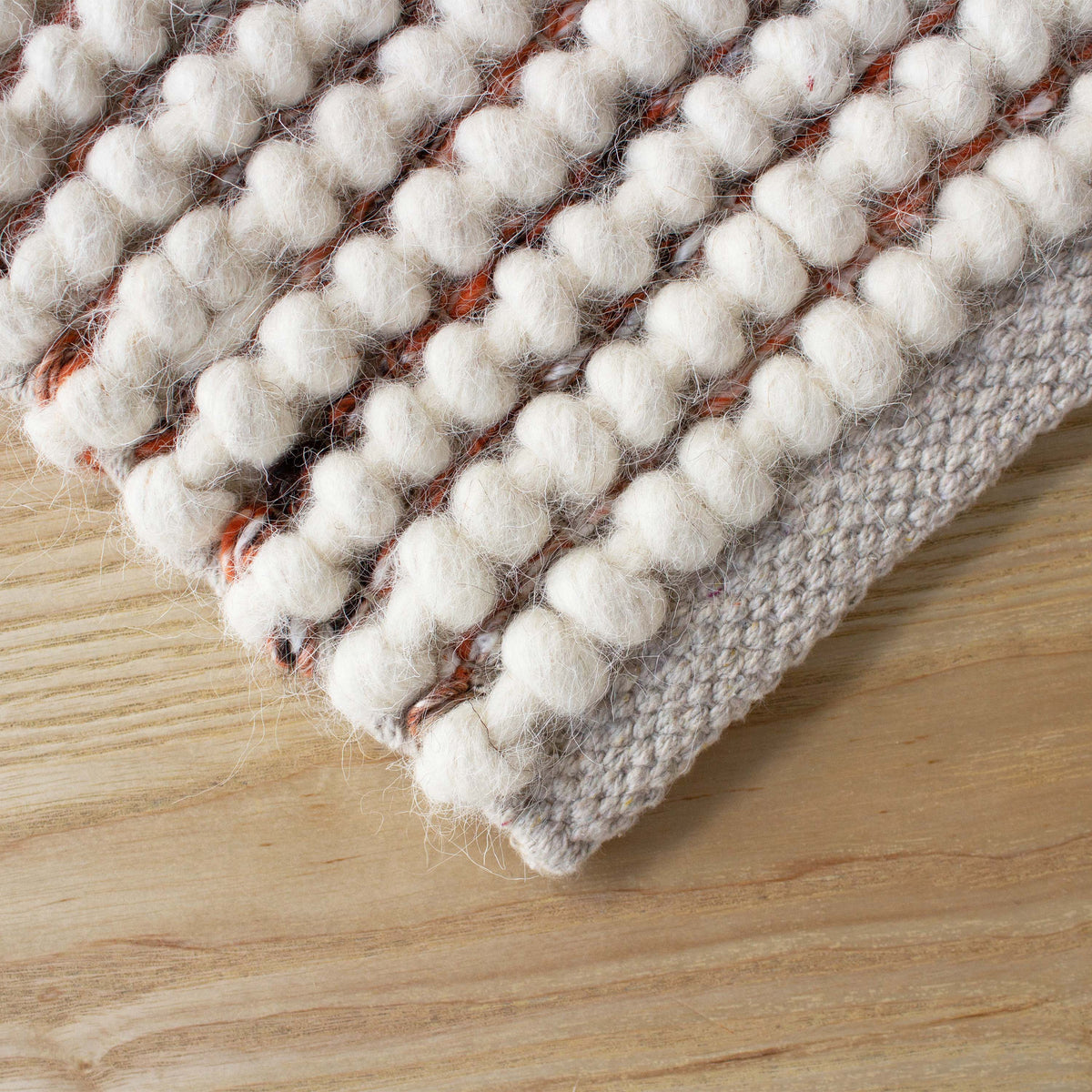 Corner of the chunky knit rug on a light timber floor