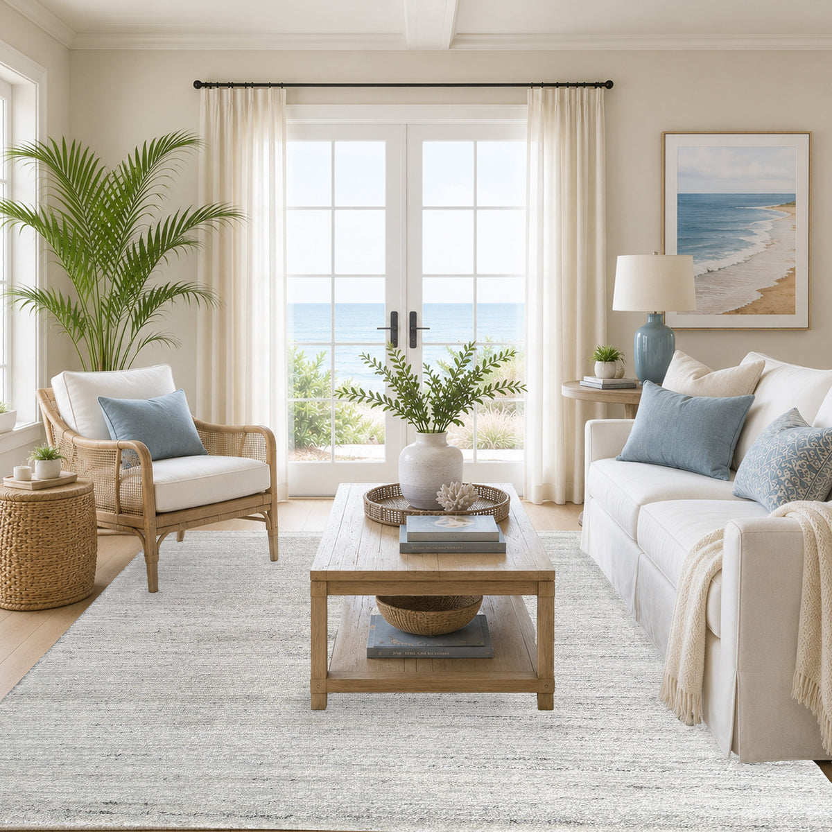 Pale grey rug in a coastal living room with a rattan armchair, timber coffee table and palm