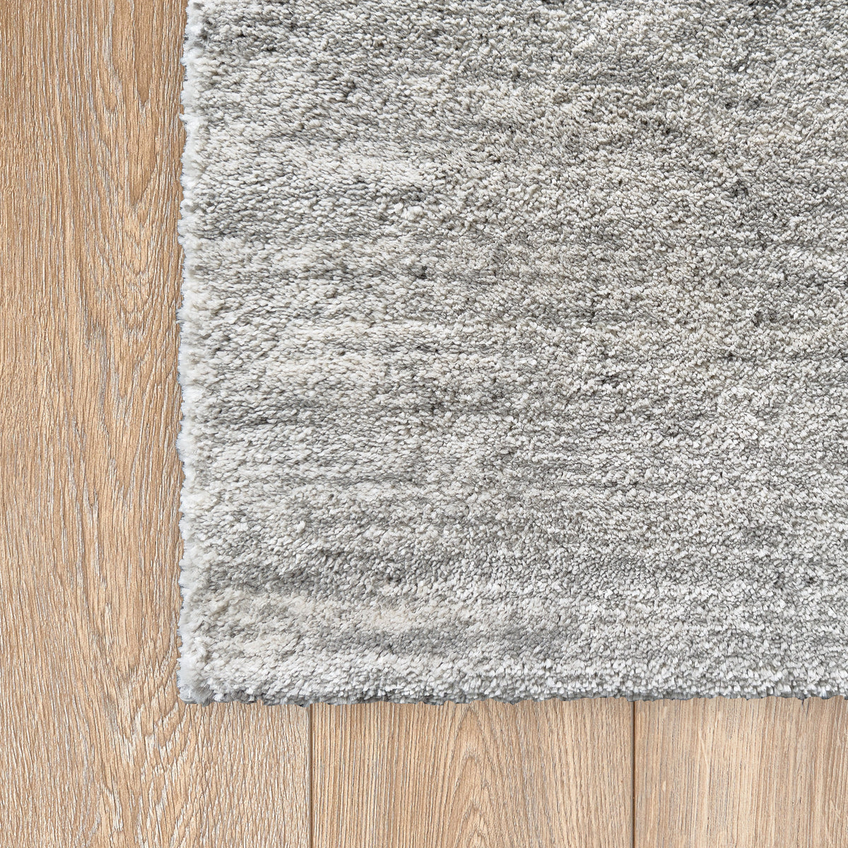 Corner of the pale grey rug on a light timber floor