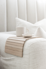 Arm Chair Side Rest — flexible wooden sofa tray in natural wood finish, styled with coffee cup on neutral armchair.