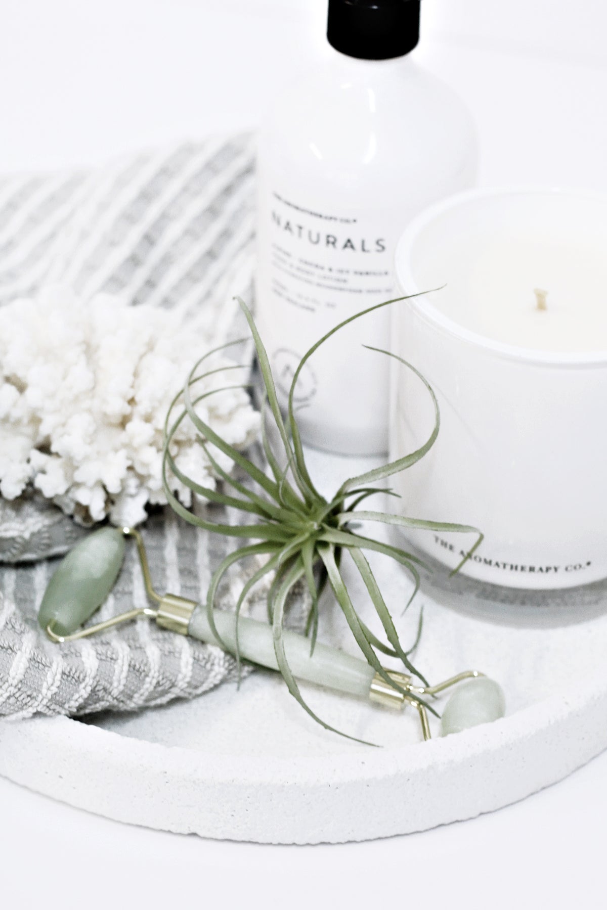 Artificial pineapple air plant faux tillandsia 15cm styled on a white tray with candle and self-care accessories in neutral tones
