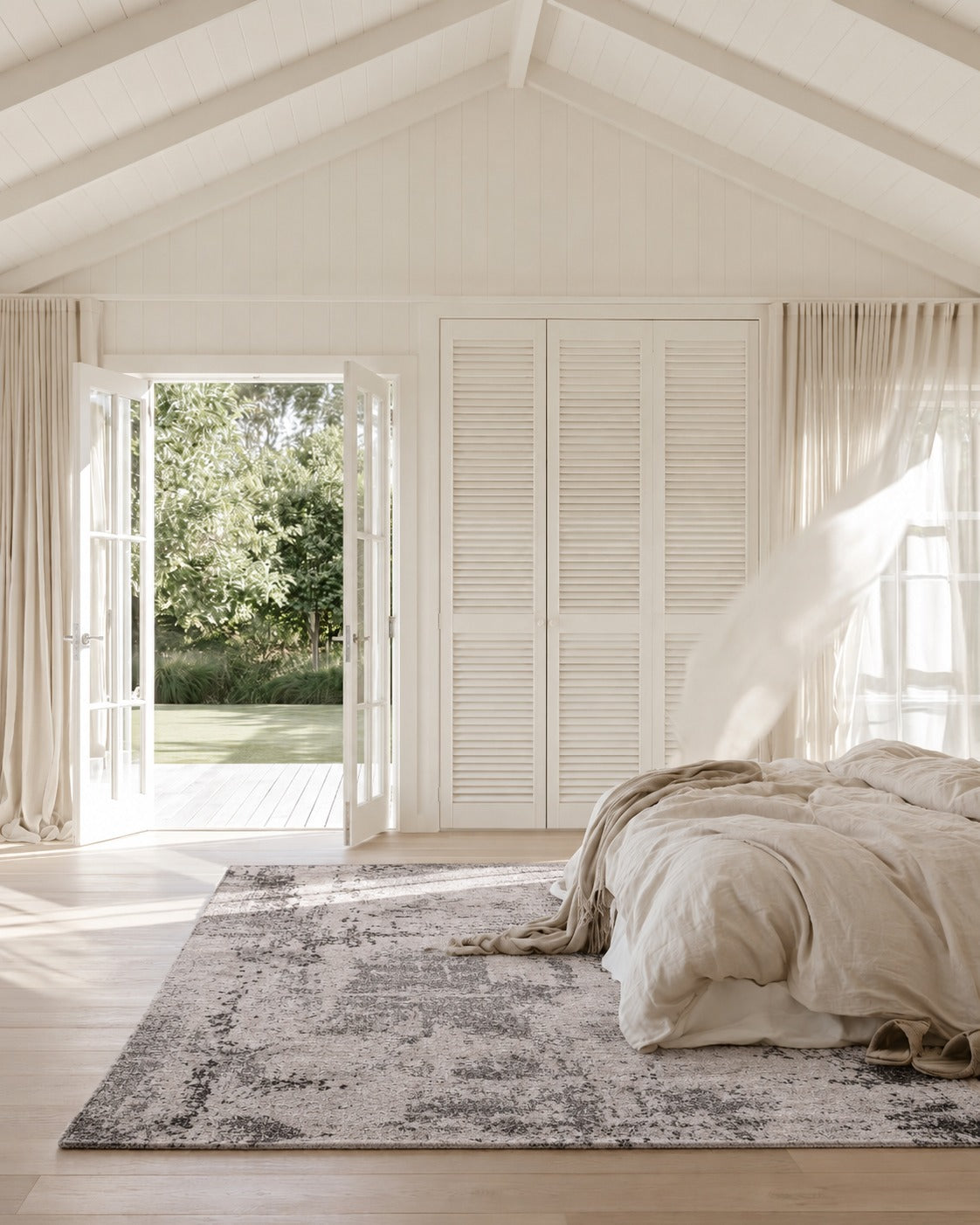Asana Vintage Light Grey and Black Rug beneath a linen dressed bed in a white bedroom with louvre wardrobe doors