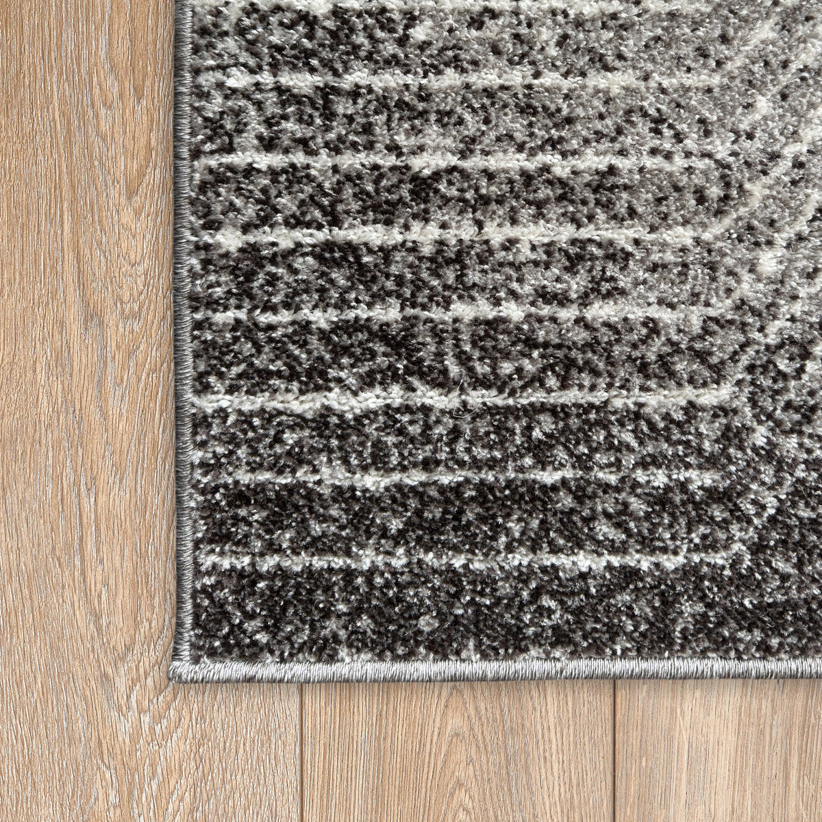 Corner of the charcoal and white striped rug on a timber floor