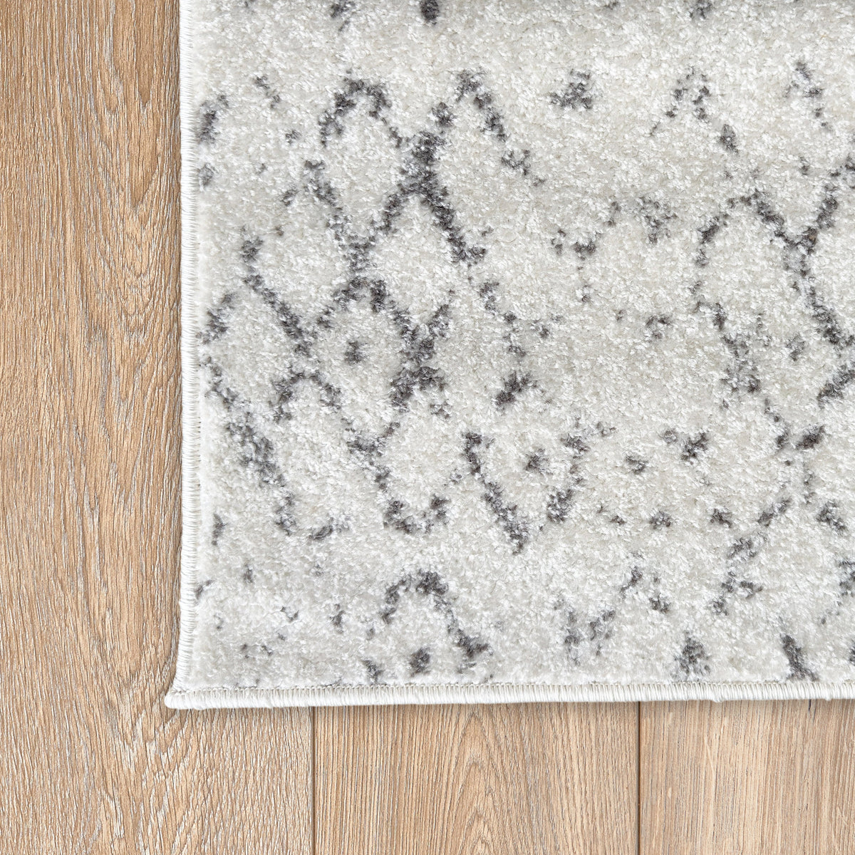 Corner of the ivory Aztec rug on a timber floor showing the grey diamond pattern