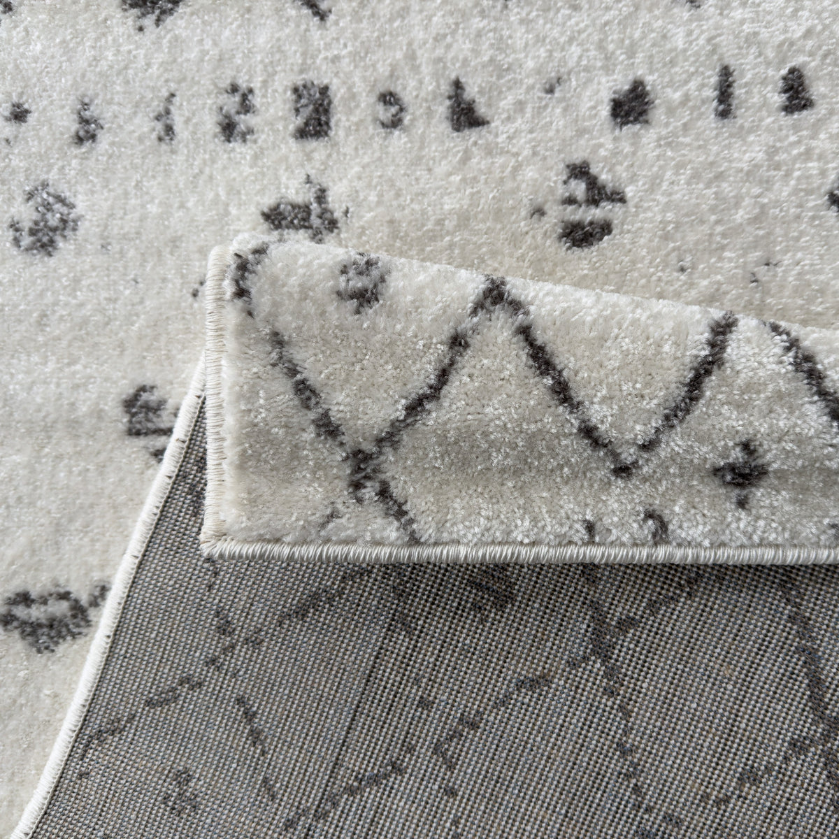 Folded corner of the ivory rug showing the pattern on the underside