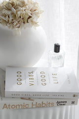 Atomic Habits book styled on bedside table with white vase and soft neutral decor