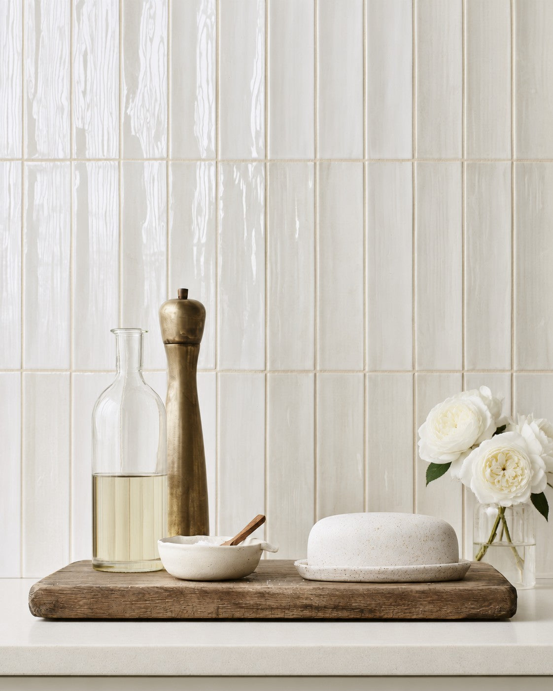 Ivory Austin roses in a small glass jar beside a speckled butter dish on a rustic timber board