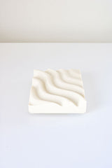 A Ripple Soap Tray made by Utilize Studios, featuring a white plate with a wavy pattern on it.