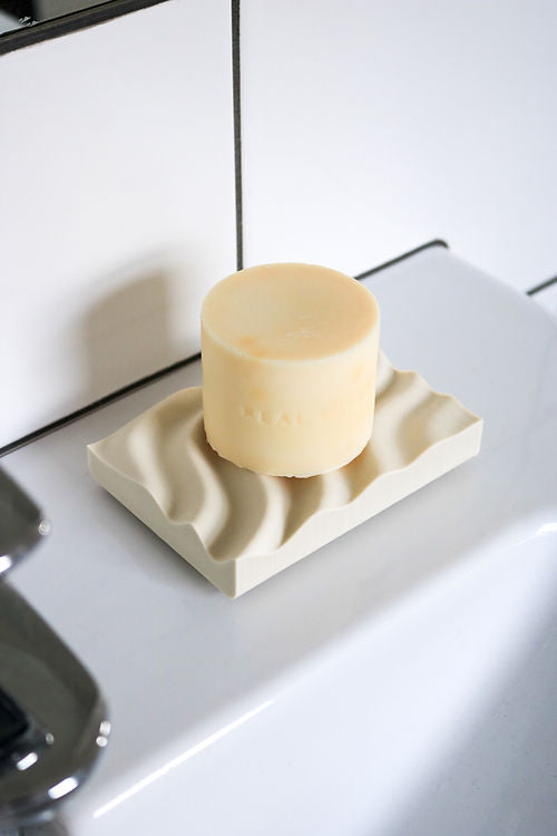 A 3D printed Ripple Soap Tray made from recycled PLA plastic is seen resting on top of a sink, placed neatly on the Tidal Tray. (Brand Name: Utilize Studios)