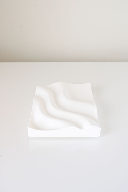 A 3D printed white plate with a wavy pattern on it, made from recycled plastic using Tidal Tray by Utilize Studios.