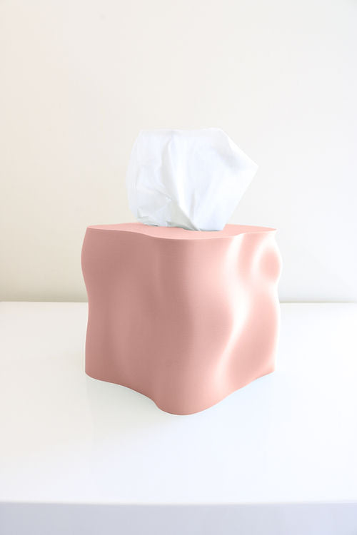 A pink Ebb tissue box sitting on top of a white table, ensuring Utilize Studios' product's safety by avoiding extreme temperatures.