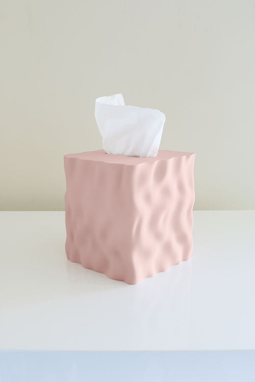 A pink Flow Tissue Box made of 3D printed recycled PLA plastic, sitting on top of a white table by Utilize Studios.