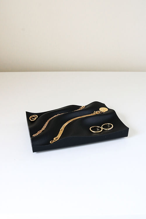 A 3D printed Utilize Studios Tidal Tray made from recycled plastic, adorned with elegant gold jewelry.