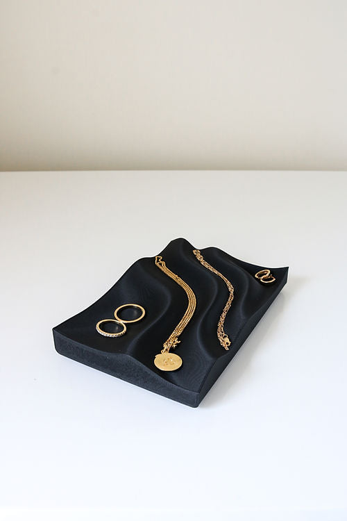 A stylish Utilize Studios Tidal Tray featuring gold jewelry, made from recycled plastic and 3D printed.