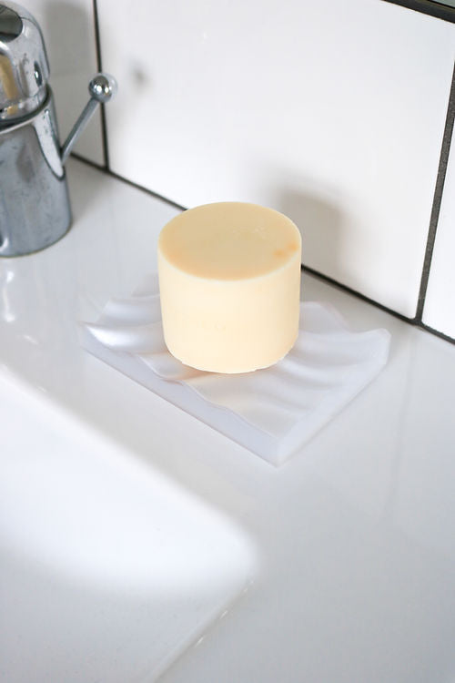 A Ripple Soap Tray from Utilize Studios sits on top of a white sink.