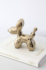 Gold ceramic balloon dog sculpture styled on top of a white gratitude journal for playful modern home décor
