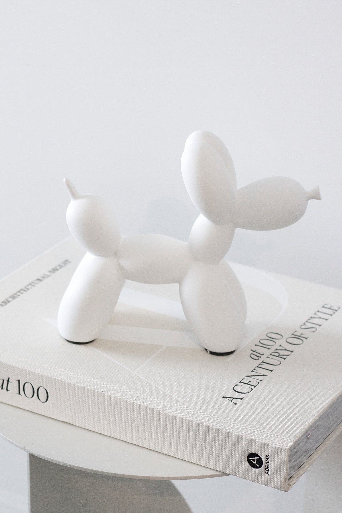 White ceramic balloon dog sculpture on a stack of coffee table books