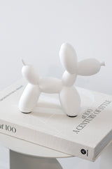 White ceramic balloon dog sculpture styled on coffee table book; playful modern decorative ornament for home styling.