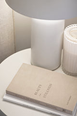 Beauty in the Stillness book by Karin Hadadan styled on a bedside table with a lamp and candle, promoting mindfulness, presence, and slow living.