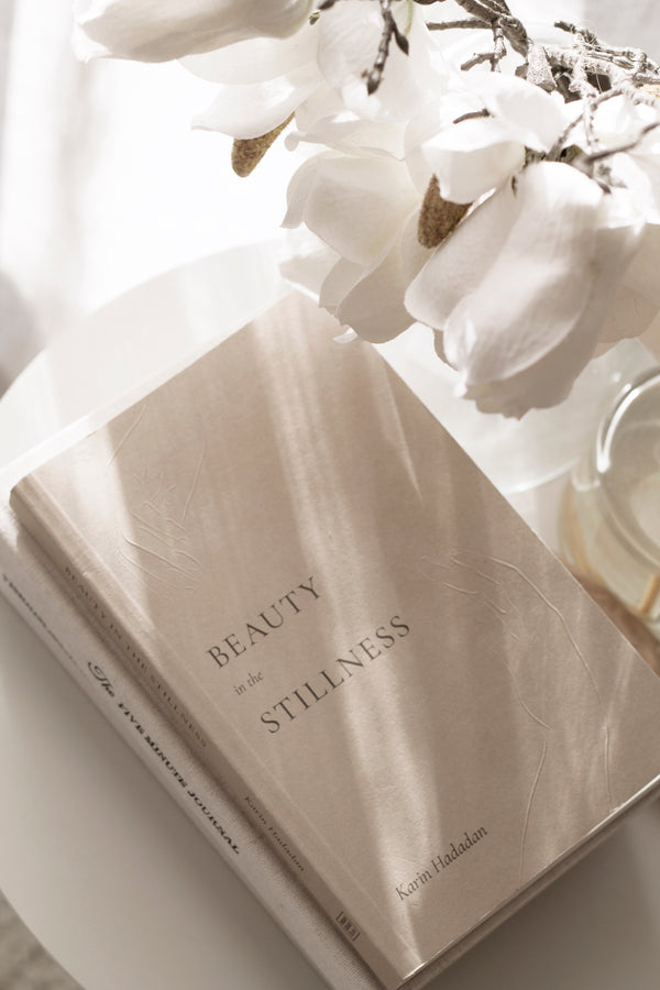 Beauty in the Stillness book by Karin Hadadan – poetry for mindfulness, healing, and calm living with white flowers in the background