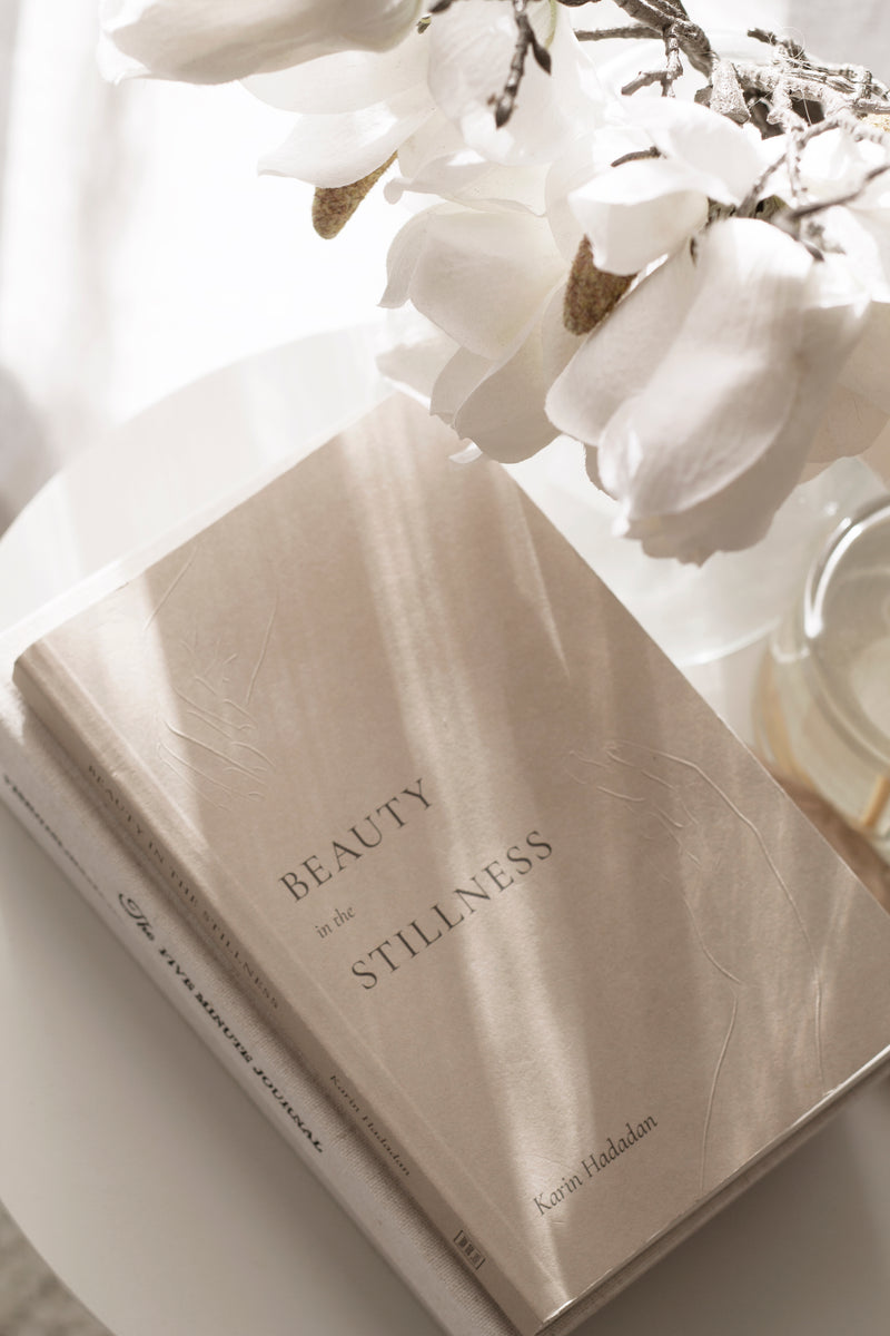 Beauty in the Stillness book by Karin Hadadan – poetry for mindfulness, healing, and calm living with white flowers in the background