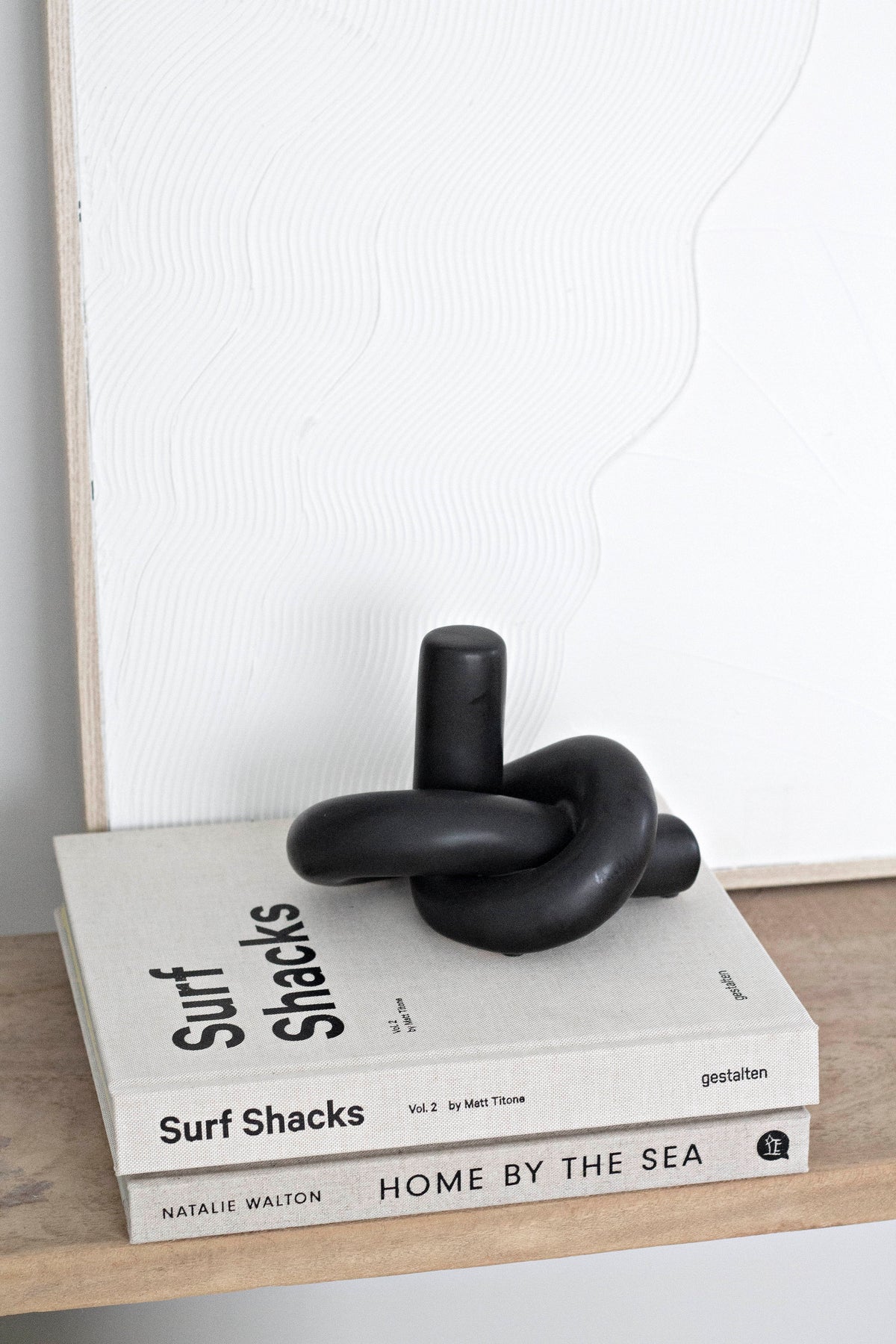 Black Knot Ornament on two stacked books leaning against a framed print