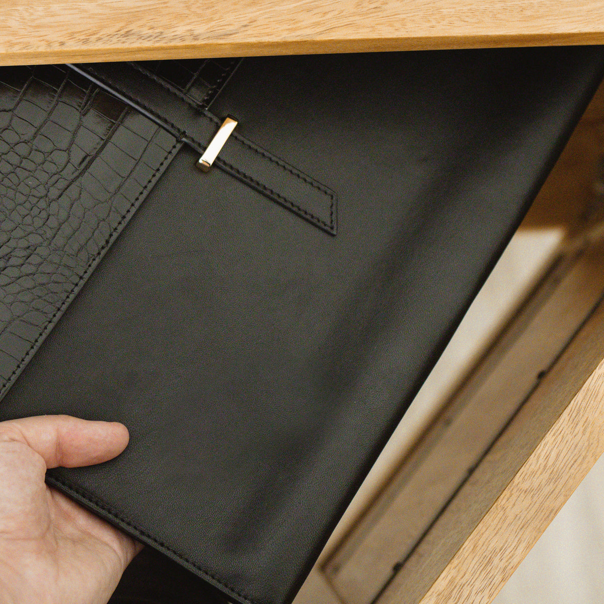 Hand opening the Black Penelope laptop sleeve to show the interior