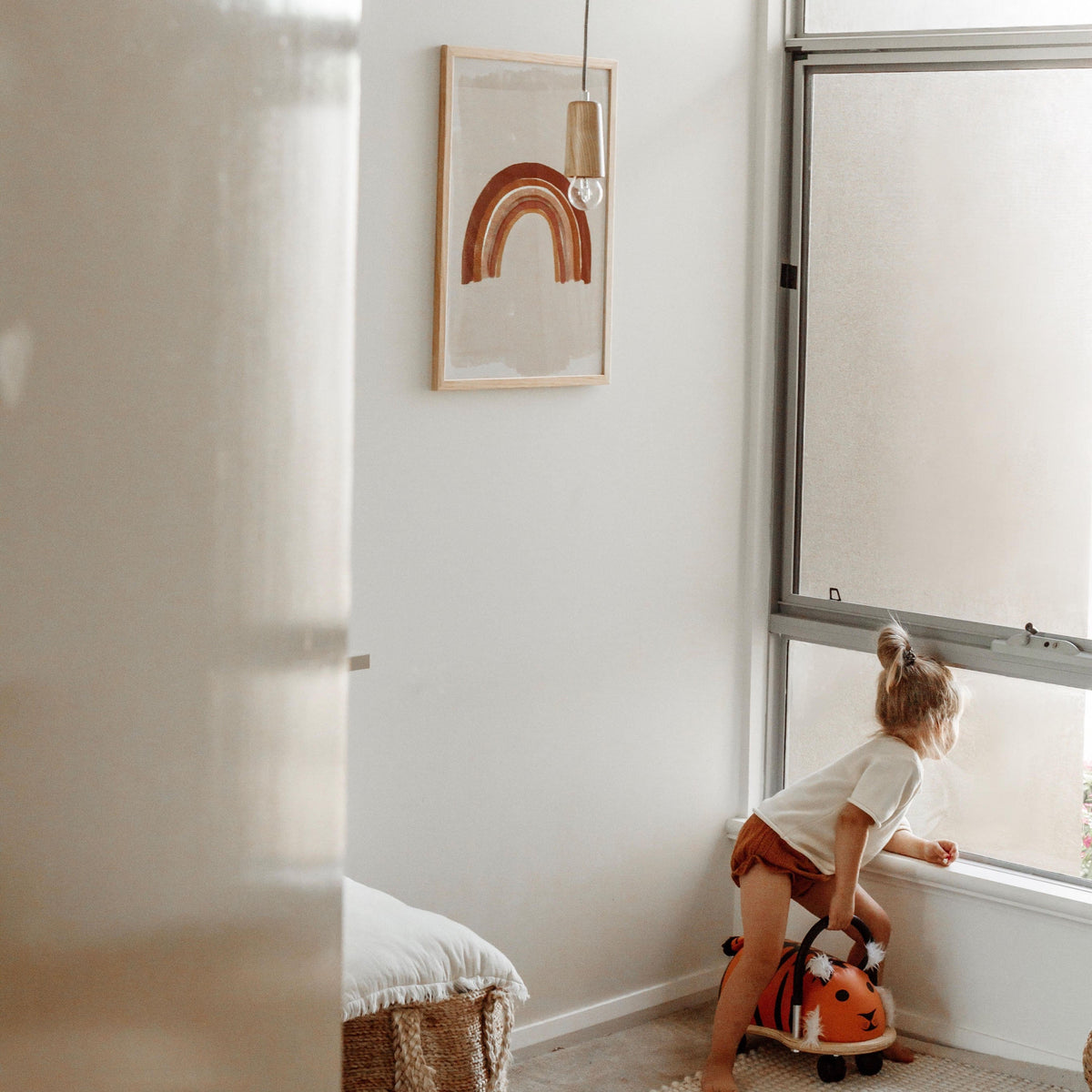 Boho Rainbow print in a natural frame in a bright nursery with a child by the window