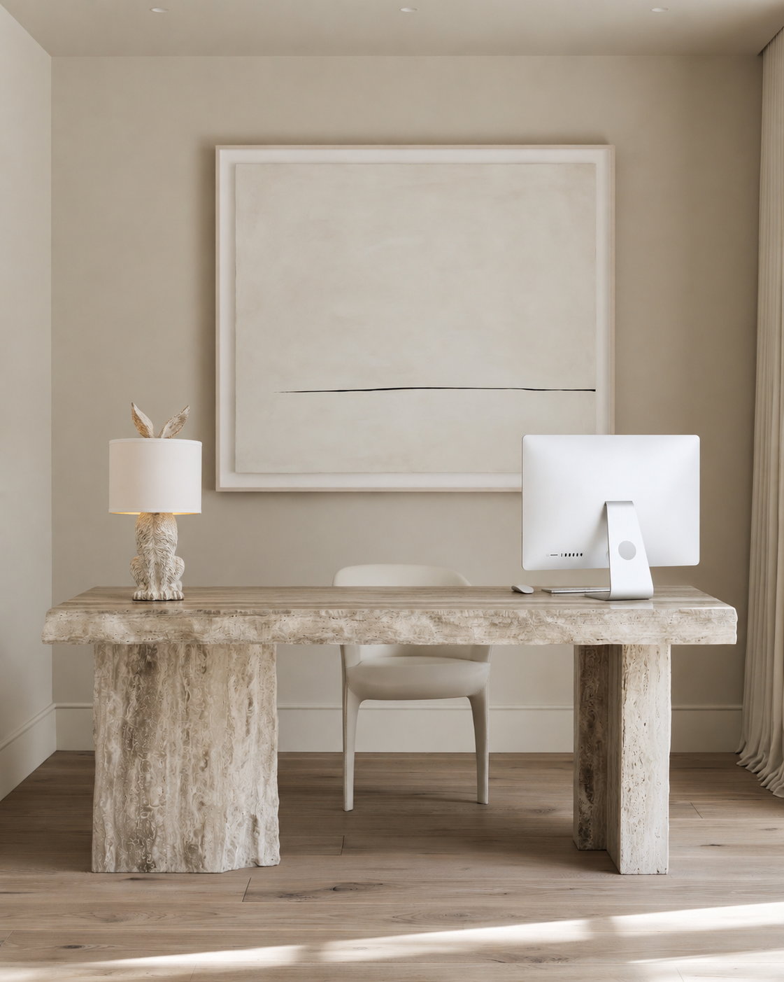 Bunny table lamp in stone texture with white shade and gold lining on a travertine desk in a home office
