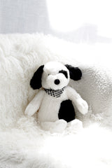 Buster the Puppy soft toy by Lily & George styled on a nursery bed with neutral bedding