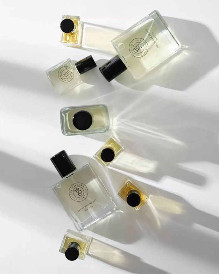 Perfume oil bottles scattered diagonally on a white surface in soft light