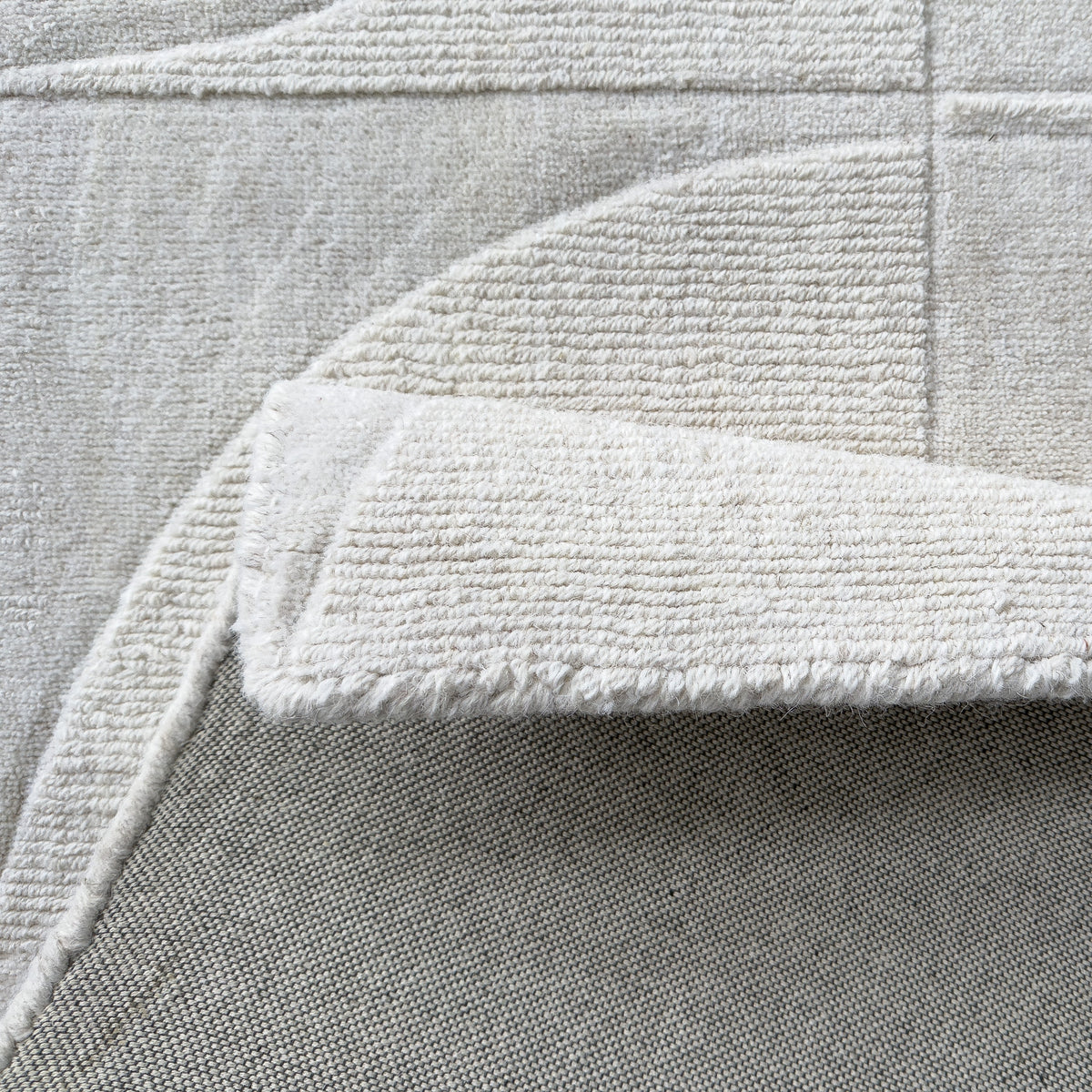 Ivory wool rug folded back to show the backing