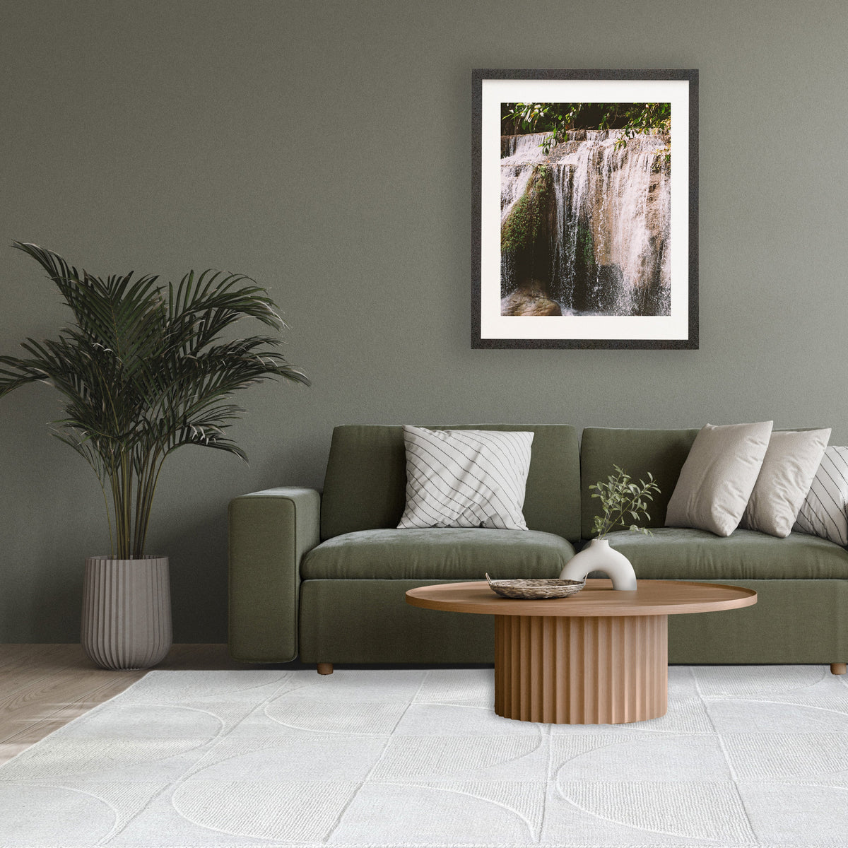 Ivory rug under a round ribbed timber coffee table in front of a green sofa with a potted palm
