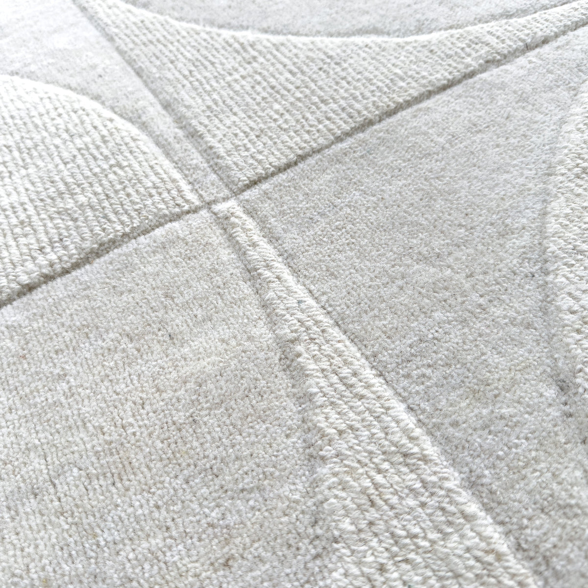 Close view of the overtufted arcs in the ivory wool pile