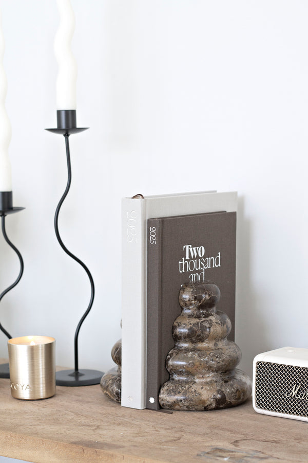 Dark marble Casa bookends with unique veining styled with books, candle, and modern accessories on a wooden console.