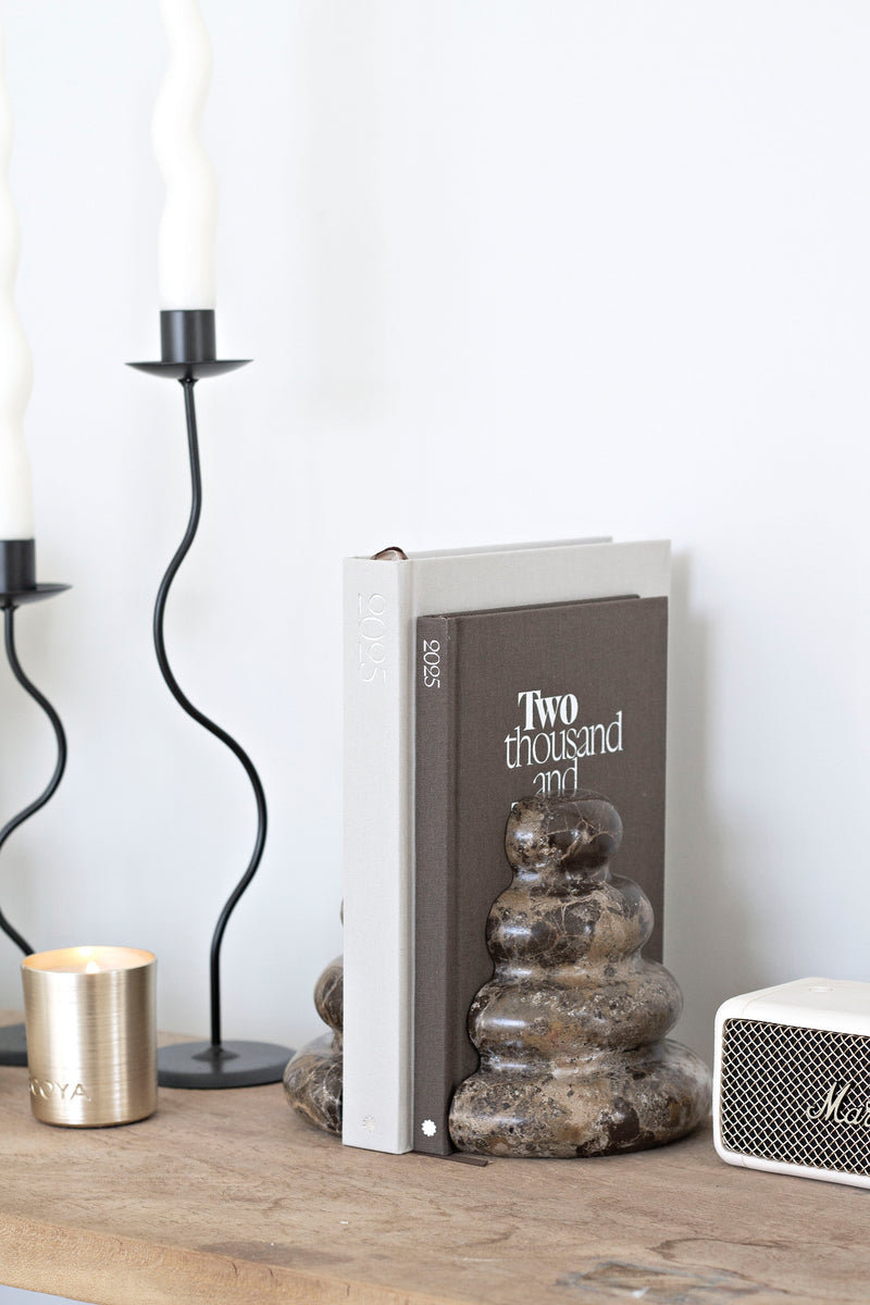 Dark marble Casa bookends with unique veining styled with books, candle, and modern accessories on a wooden console.