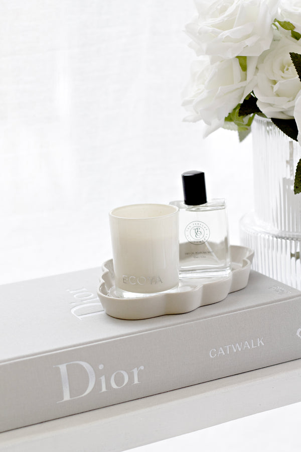 White ceramic cloud-shaped jewellery tray styled with Ecoya candle and perfume on Dior Catwalk book; sculptural decor piece.