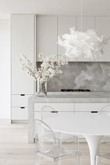 White Cloud Pendant paper lamp shade in a white kitchen with fresh flowers and a clear acrylic chair