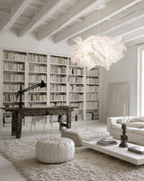White Cloud Pendant paper lamp shade in a light living room with built-in bookshelves and a white pouf