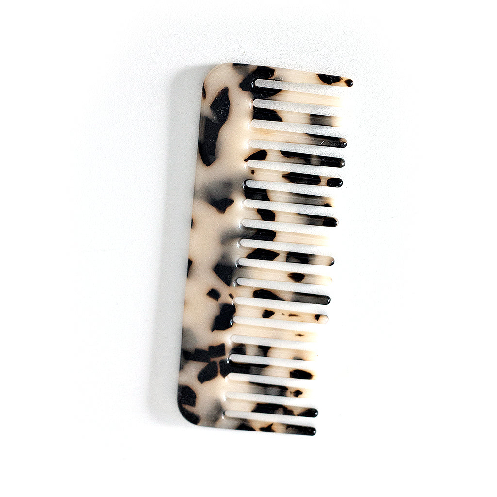 Acetate comb in cream with black speckle, wide tooth, on a plain background