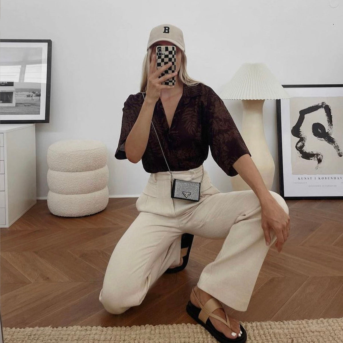 Woman crouching for a mirror selfie beside the Copenhagen print in a black frame