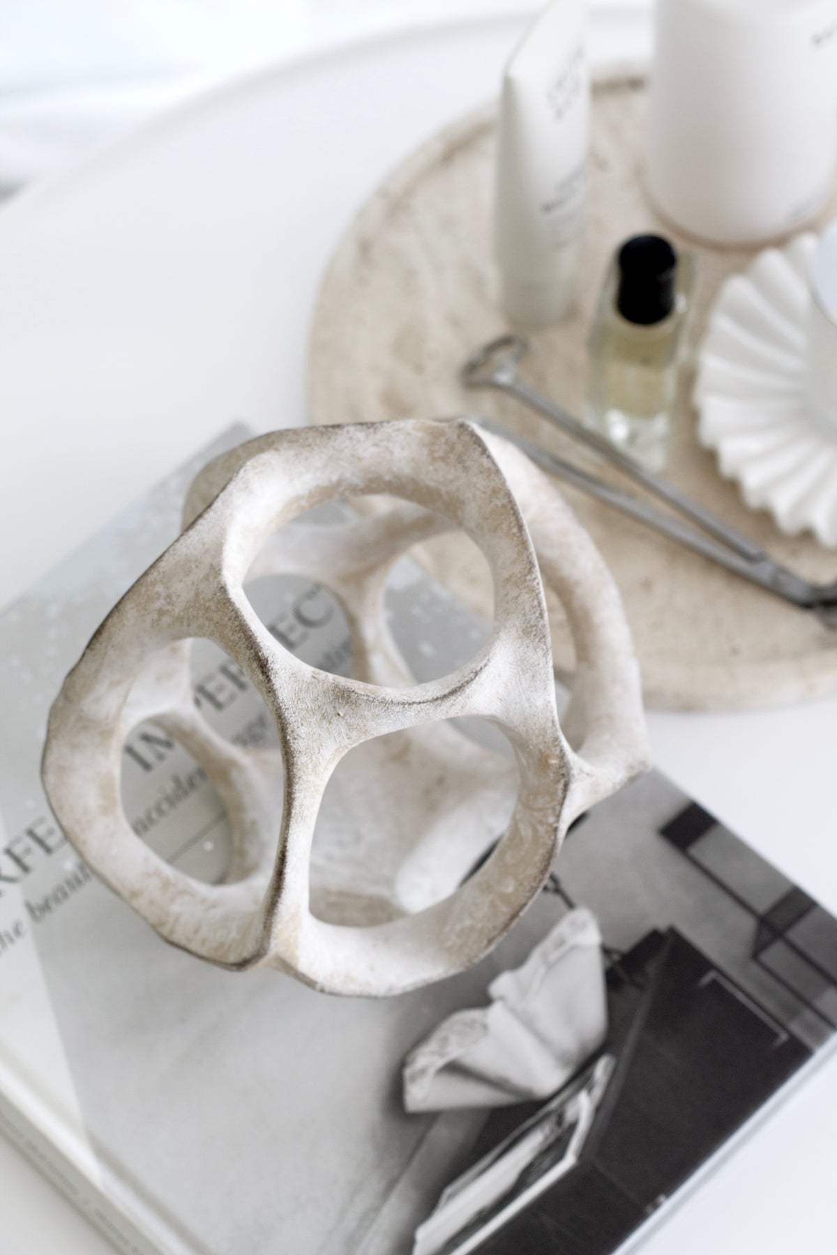 Cosmo resin sphere on stacked books beside a travertine tray