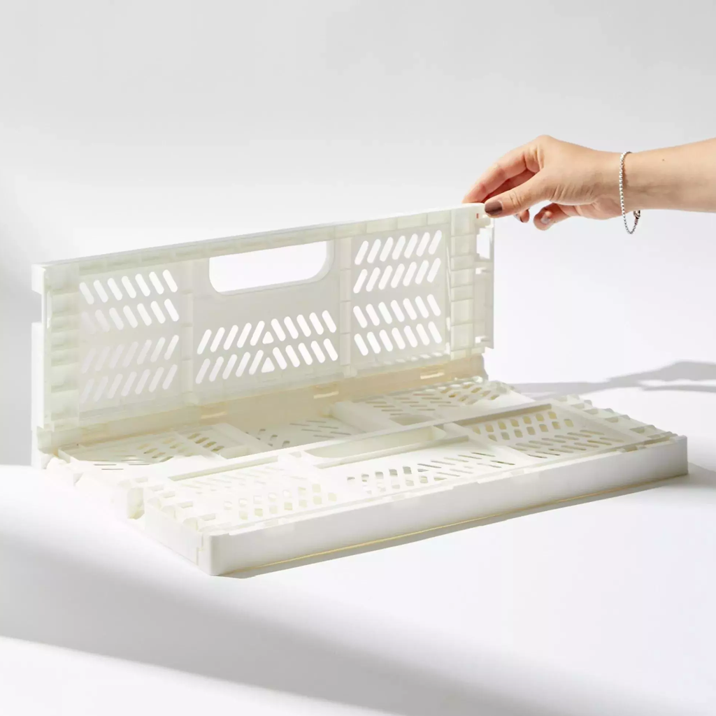 A hand lifting the folded crate flat, showing how it collapses for storage